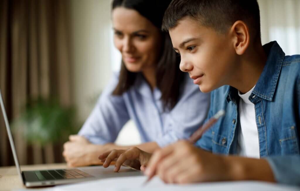 Homeschooling parent watching her son work on an online course