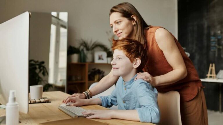 Mother and son smiling while son studies science online