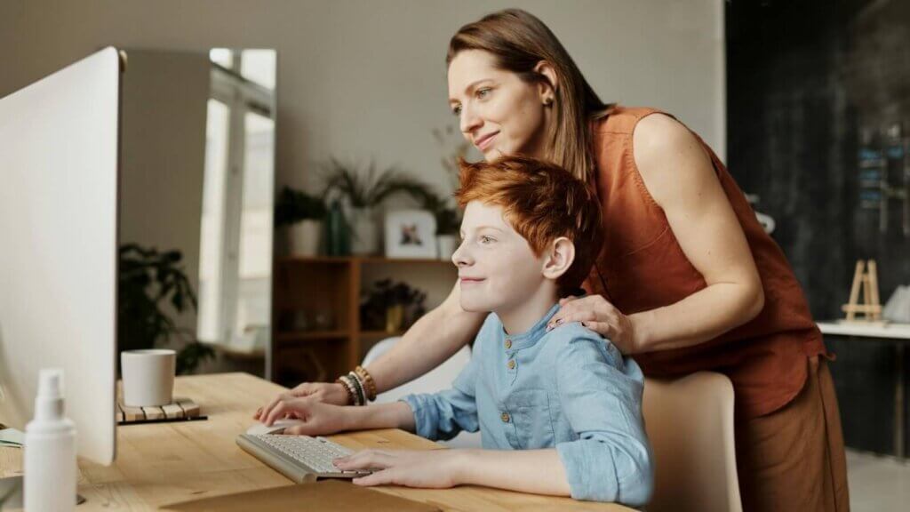 Mother and son smiling while son studies science online